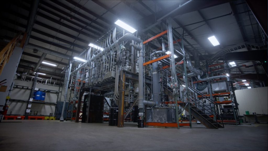 A picture of the inside of AmeriCarbon's manufacturing facility containing lots of small metal pipes going vertically and horizontally throughout a tight space.